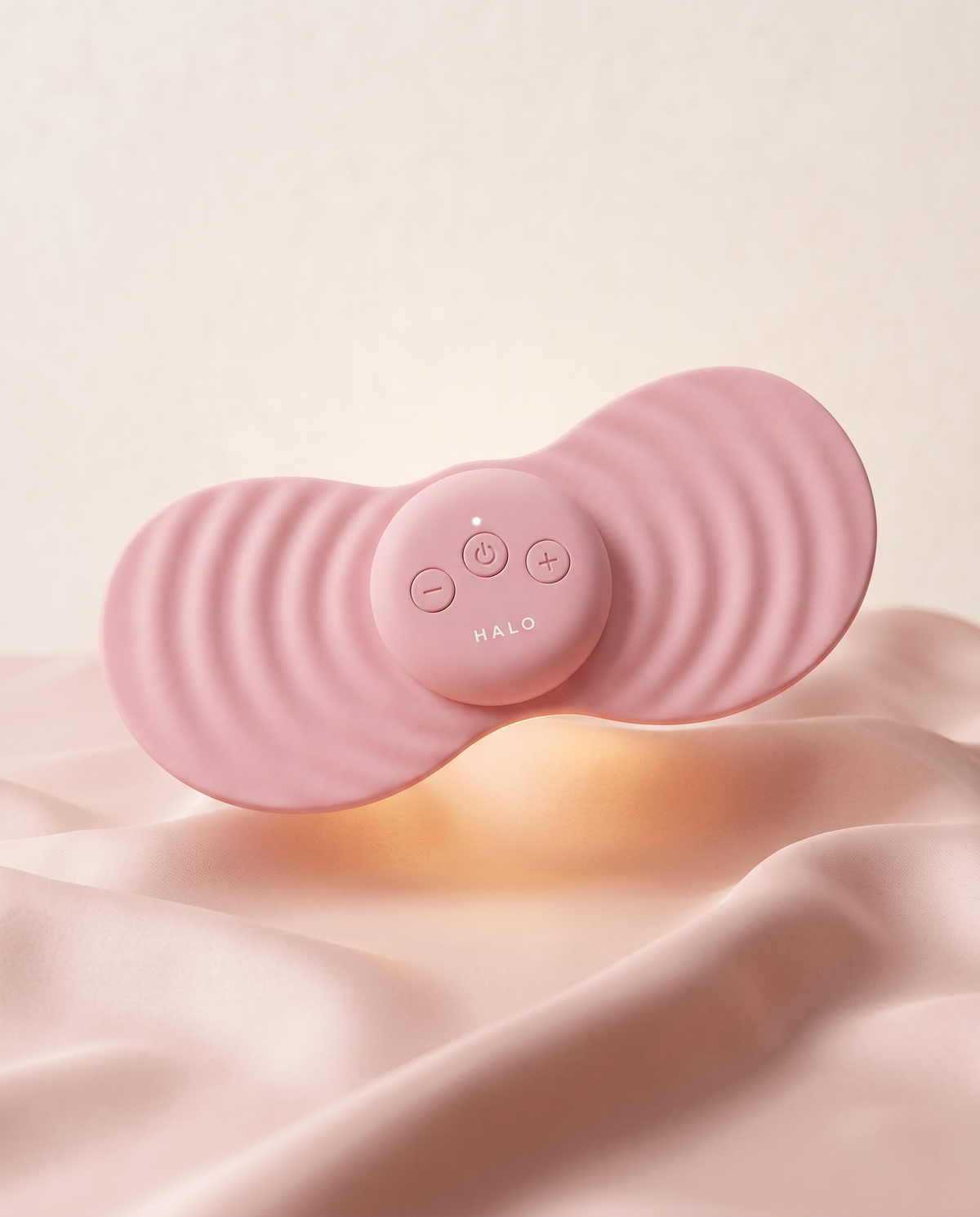 HALO rose heated massager floating above blush silk